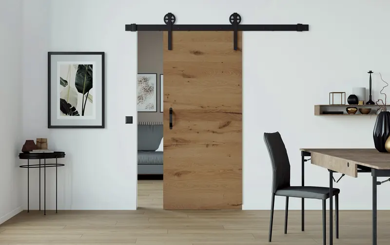 LOBO Holzschiebetür in Eiche mit schwarzer Laufschiene, eingebaut im Wohnraum